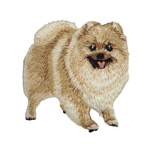 May include: A brown and white embroidered patch of a Pomeranian dog with a pink tongue sticking out.