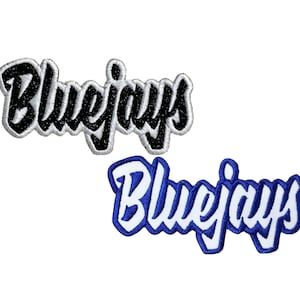Peut inclure: Deux patchs brodés avec le mot "Bluejays" dans une police de caractères stylisée. Le patch du haut est noir avec des coutures blanches, et le patch du bas est bleu avec des coutures blanches.