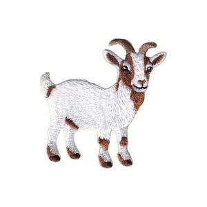 May include: An embroidered iron-on patch featuring a goat standing in profile. The goat has white fur on its body and head, with brown patches on its face, neck, and legs. It has two small horns, pointed ears, and a short tail, all rendered in thread.