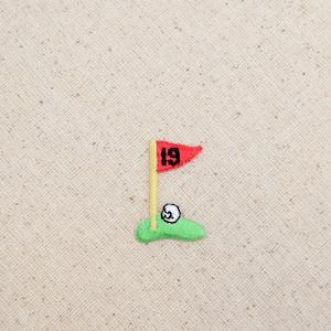 May include: Embroidered patch of a golf green with a golf ball and a red flag with the number 19 on it.