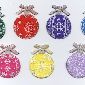 Może przedstawiać: Zestaw siedmiu haftowanych ozdób choinkowych w różnych kolorach i wzorach. Ozdoby mają kształt kuli z kokardką na górze. Kolory obejmują zielony, czerwony, fioletowy, niebieski, różowy, żółty i lawendowy.