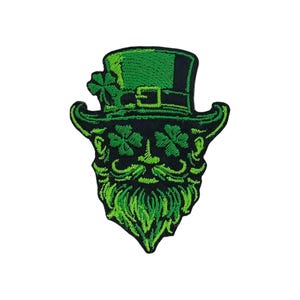 Peut inclure: Écusson brodé représentant un visage de leprechaun vert avec un chapeau haut de forme et des trèfles. Le design comprend une barbe verte, une moustache et des trèfles pour les yeux. Le chapeau a une boucle et un trèfle sur le côté.