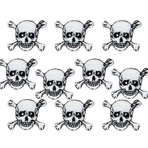 Könnte beinhalten: Zehn weiße Bügelbilder mit Totenkopf und Knochen. Der Totenkopf und die Knochen sind schwarz.