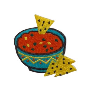 May include: Embroidered patch featuring a bowl of salsa with tortilla chips. The salsa is red with dark green flecks, set in a turquoise bowl with a yellow and turquoise border. Two yellow tortilla chips with black dots are also included.