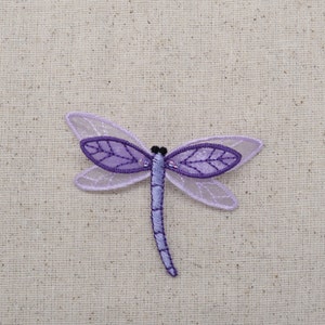 May include: A purple and white embroidered dragonfly applique with a beaded body.