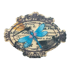 May include: An embroidered patch featuring a blue dragonfly with pink accents, set against a vintage postcard background with the text "Arte Postal" and a decorative frame.