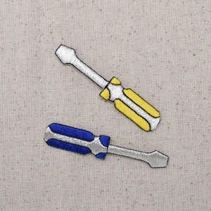 May include: Two embroidered iron-on patches of screwdrivers. One is yellow with a silver handle and the other is blue with a silver handle.