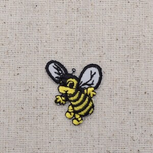 May include: A yellow and black embroidered bee with white wings. The bee is cartoon-like and has a friendly expression.