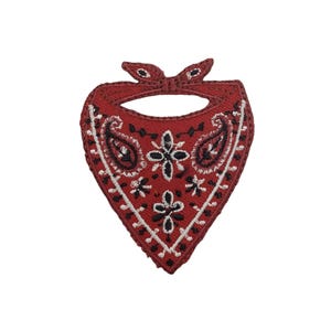 May include: A triangular embroidered patch shaped like a folded bandana. The patch is deep red with intricate black and white paisley and floral patterns stitched throughout. It features a knotted top section and a stitched border edge.