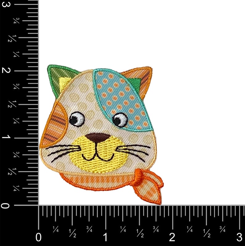 May include: A colorful patchwork cat face applique with a yellow smile, orange and white striped ears, and a blue and white polka dot patch on the head. The cat is wearing a bright orange scarf.