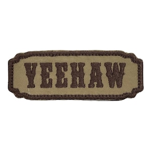 Puede incluir: Un parche de tela beige con texto bordado en marrón que dice "YEEHAW".