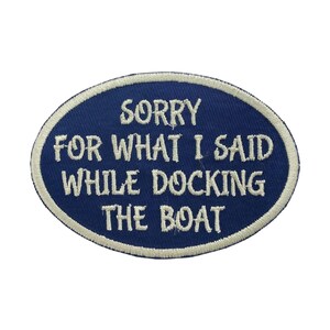 May include: Oval-shaped navy blue patch with white embroidered text. The text reads "SORRY FOR WHAT I SAID WHILE DOCKING THE BOAT". The patch has a white border and is likely designed to be sewn onto clothing or accessories.