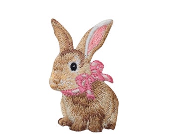 May include: A brown embroidered bunny with pink ears and a pink bow. The bunny is sitting with its head tilted to the side.