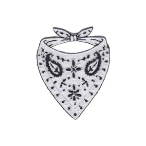 May include: A white embroidered patch in the shape of a triangular bandana with a tied knot at the top. The fabric features a black stitched paisley pattern and floral motifs, with a black border outlining the entire triangular shape of the patch.