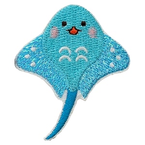 May include: Embroidered patch featuring a cartoon stingray in shades of blue. The stingray has a smiling face with pink cheeks, white accents, and a long, slender tail. This patch is designed for decorative purposes.