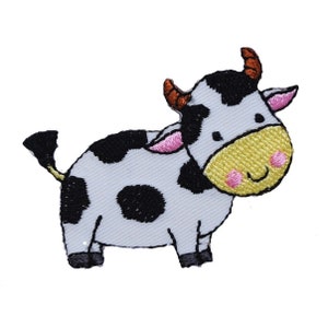May include: A white and black embroidered cow patch with brown horns, pink ears, and a yellow smiling face.