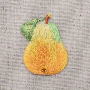 May include: A yellow pear with a green leaf embroidered on a beige fabric background.