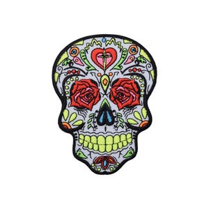 Peut inclure: Un patch brodé de sucre coloré avec des roses rouges pour les yeux, un motif floral vert et jaune et un fond blanc.