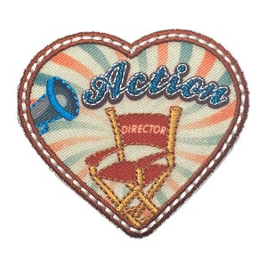 May include: A heart-shaped embroidered patch with a director's chair, a megaphone, and the word "Action" in sparkly blue letters. The background is a vintage-style striped pattern in shades of peach, cream, and blue.