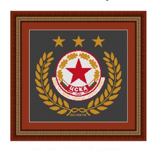 Puede incluir: Un diseño de punto de cruz enmarcado que presenta el logotipo del CSKA Sofía, un club de fútbol búlgaro. El logotipo es una estrella roja dentro de un círculo rodeado por una corona de laurel dorada. El texto "CSKA 1948" se muestra dentro del círculo. Tres estrellas doradas se muestran sobre el logotipo. El año "2018/19" se muestra debajo del logotipo.