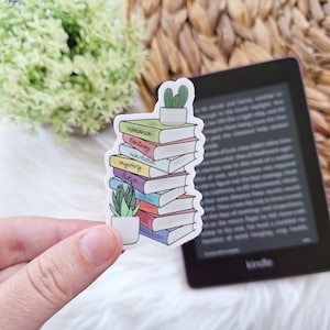 May include: A sticker of a stack of colorful books with the words "romance", "fantasy", "non-fiction", "mystery", and "fiction" written on them. A small potted cactus is on top of the stack.