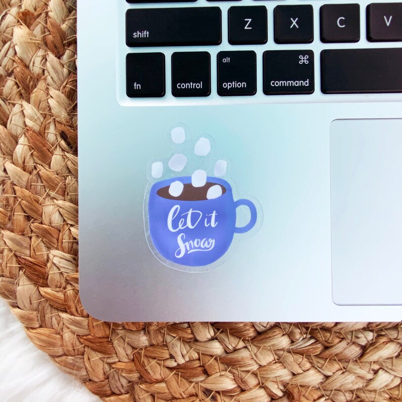 May include: A blue and white sticker with a mug of hot chocolate and marshmallows. The text on the sticker says "Let it Snow".