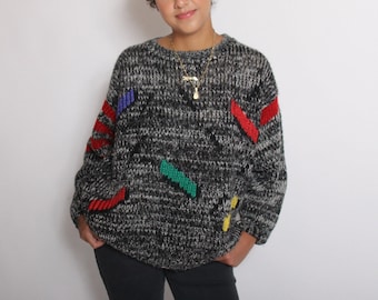 May include: A gray and black knit sweater with colorful geometric patterns. The sweater has a crew neck and long sleeves.