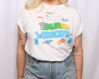 May include: White t-shirt with a graphic print of animals and the text "Save Our Wildlife".