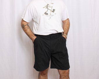 May include: A white t-shirt with a graphic of a stick figure wearing hiking boots and carrying an axe. The text on the shirt reads "You Got Water?"  The person is wearing black shorts.