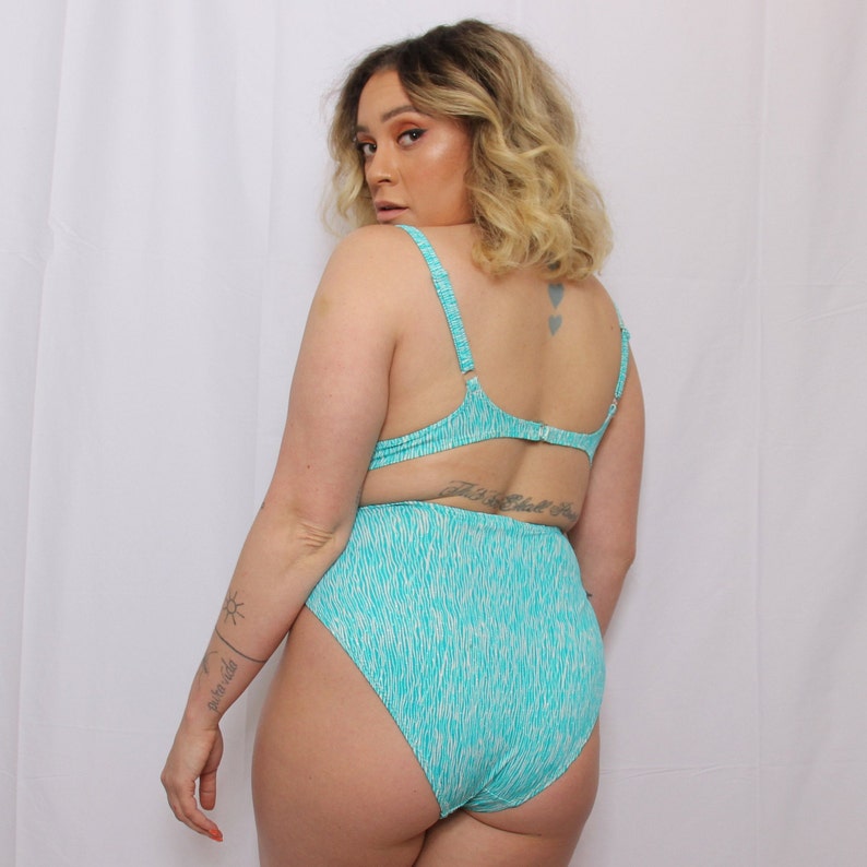 Puede incluir: Un traje de ba&ntilde;o de color turquesa y blanco con estampado, con la parte de abajo de cintura alta y la parte de arriba de halter.