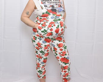 May include: A sleeveless white top with the text "GROBER PREIS VON DEUTSCHLAND" and a racing car graphic, paired with white capri overalls. The overalls feature a red rose floral pattern with green leaves and blue accents.