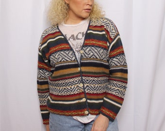 May include: A multi-colored striped cardigan with a geometric pattern. The cardigan has a button-up front and long sleeves.