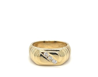 May include: A gold ring with a rectangular face and three small diamonds set diagonally. The ring has a ribbed design around the band. The ring is a classic piece of jewelry.