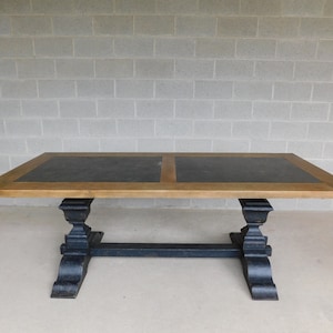 May include: A rectangular dining table with a light brown wooden frame and a dark gray tabletop. The table has a black base with decorative supports. The table is approximately 72 inches long and 40 inches wide.