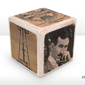 May include: A wooden cube with four sides featuring images related to Nikola Tesla. One side shows a portrait of Tesla, another shows a diagram of a Tesla coil, and a third side shows a diagram of a rotating magnetic field. The fourth side features text that reads "I'll give you a power that will make you master of the world."