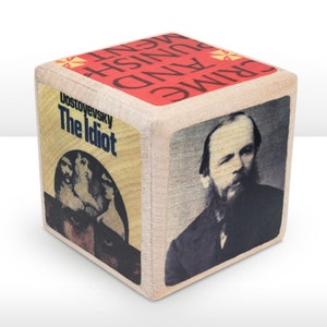 May include: A wooden block featuring book covers and a portrait. One side displays "Dostoyevsky The Idiot", another shows a portrait, and the top reads "CRIME AND PUNISHMENT". The block is a literary-themed decorative item.