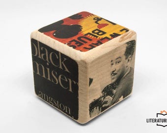 May include: A wooden cube with printed images and text. One side features a black and red design with the words "WEAR BLUES". Another side displays a black and white image of a man with a guitar. The text "black miser angston" is on another side.