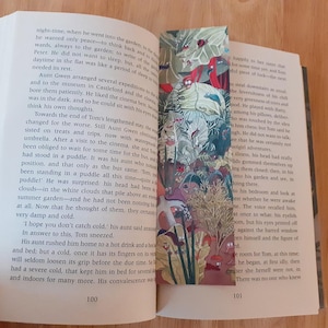 May include: Open book with a colorful bookmark featuring a whimsical garden scene with red, green, and blue elements. The book's pages feature text about a young boy named Tom who is sick and recovering.