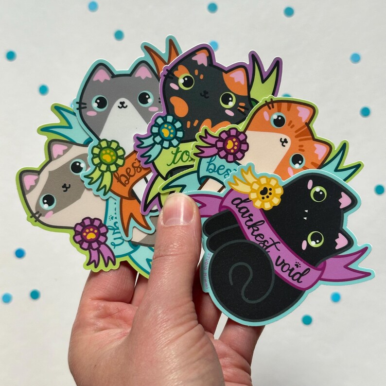 May include: Five colorful cat stickers with different colored fur and expressions. Each sticker has a ribbon with text that reads "best to be" and "darkest void".