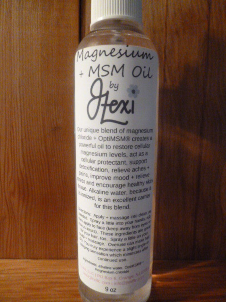 May include: A clear glass bottle with a white label that reads "Magnesium + MSM Oil by Fexi". The label describes the product as a unique blend of magnesium chloride and OptiMSM that creates a powerful oil to restore cellular magnesium levels, act as a cellular protectant, support detoxification, relieve aches and pains, improve mood and relieve stress, and encourage healthy skin tissue. The bottle is 9 oz.