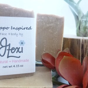 Op de afbeelding: Een Aleppo-ge&iuml;nspireerde, natuurlijke, handgemaakte zeep van Jexi, met een wit etiket waarop staat "Aleppo Inspired Face + body by Jexi Natural + Handmade net wt 4.15 oz".