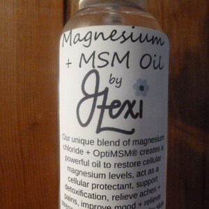 May include: A clear glass bottle with a white label that reads "Magnesium + MSM Oil by Fexi". The label describes the product as a unique blend of magnesium chloride and OptiMSM that creates a powerful oil to restore cellular magnesium levels, act as a cellular protectant, support detoxification, relieve aches and pains, improve mood and relieve stress.