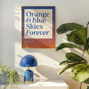May include: A framed rectangular wall art print featuring the text Orange & Blue Skies Forever in dark blue serif font on a cream background, with a reddish-brown lower section containing small text details including Year 2020 and New York Knicks.