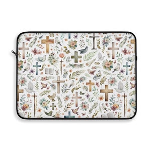 May include: A white laptop sleeve with a repeating pattern of crosses, birds, and flowers. The crosses are in various shades of brown and blue, and the flowers are in shades of pink, yellow, and green.