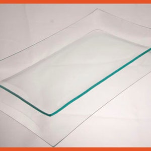 May include: Two clear glass serving trays, one with a green rim, stacked on top of each other.