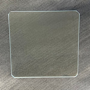 May include: A clear glass plate with slightly rounded edges.