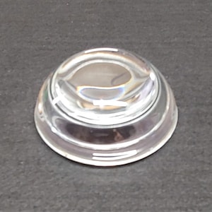 May include: A silver-colored, round, dome-shaped magnifying glass with a clear lens.