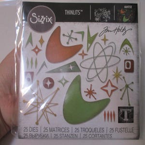 May include: A package of Sizzix Thinlits dies featuring mid-century modern shapes in orange, green, and silver. The package includes various starbursts, boomerangs, and atomic age designs. The package also includes the text "Jim Holtz".