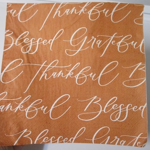May include: A brown paper napkin with the words "thankful", "blessed", and "grateful" written in white cursive script.