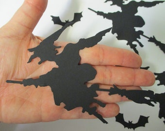 May include: Black paper cutouts of witches flying on broomsticks and bats. The cutouts are on a hand for size reference.